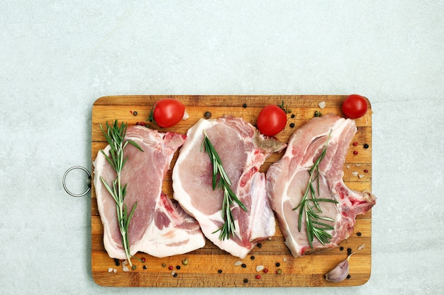 Filete de cerdo cruda en una tabla de cortar con hierbas y especias