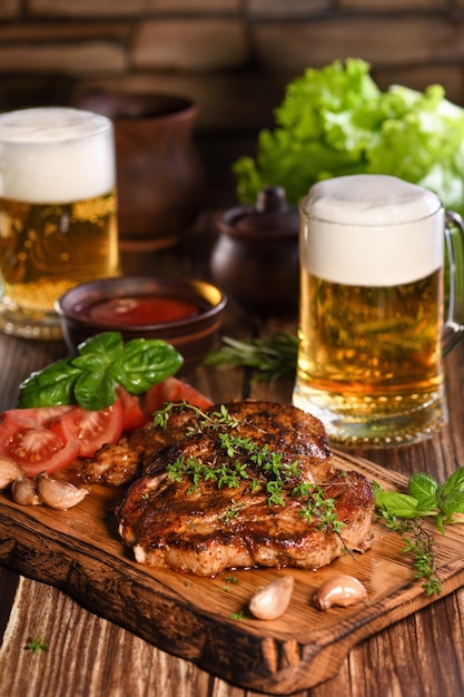 Filete de cerdo frito sobre una tabla de madera para acompañar con verduras y una jarra de cerveza.