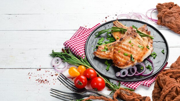 Filete de cerdo en un hueso con romero y verduras en un plato negro Vista superior Espacio de copia libre