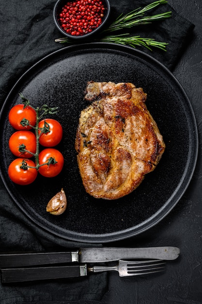 Filete de cerdo a la plancha sobre hueso con tomate. Vista superior