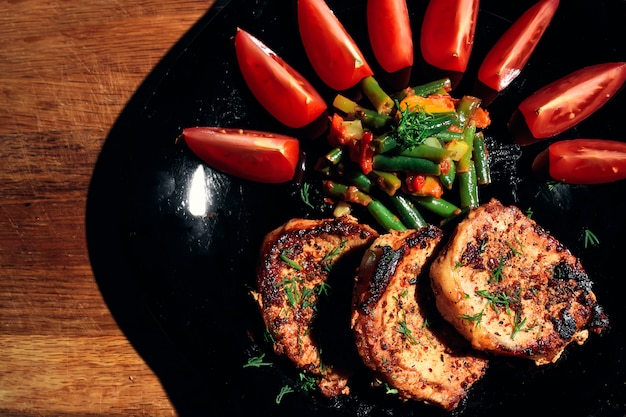 Filete de cerdo en un plato negro con verduras