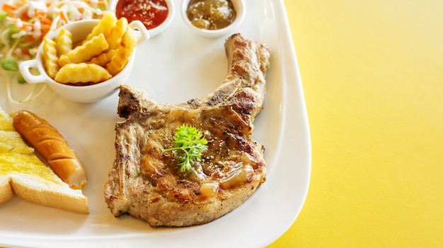 Filete de chuleta de cerdo en una mesa amarilla