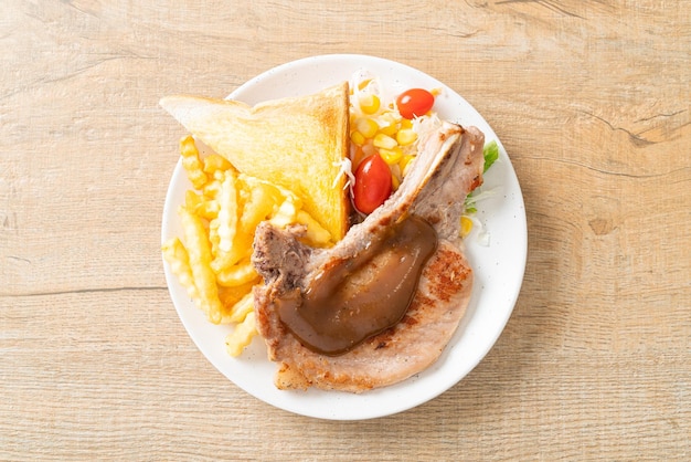 Filete de chuleta de cerdo con patatas fritas y mini ensalada en la placa blanca.