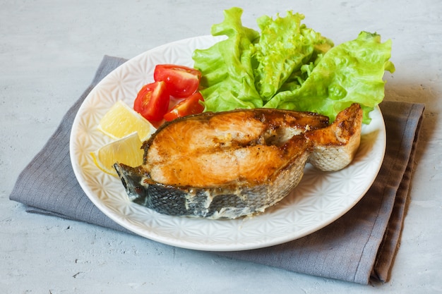 El filete coció los pescados de color salmón en una placa con las verduras frescas.