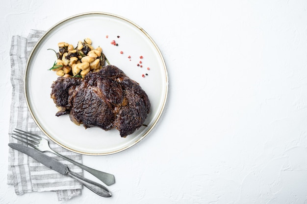 Filete de costilla cocido con frijoles blancos, sobre superficie de piedra blanca