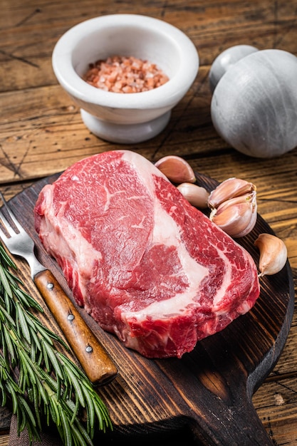 Filete de costilla cruda carne de ternera sobre tabla de madera con tomillo Fondo de madera Vista superior