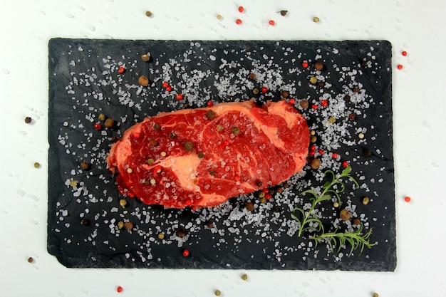 Filete de costilla crudo fresco en placa de piedra negra con sal, filete crudo con especias