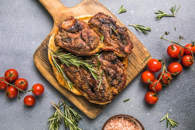 Filete de costilla a la parrilla carne de res de ternera veteado en una tabla con tomate Vista superior de fondo negro Espacio de copia