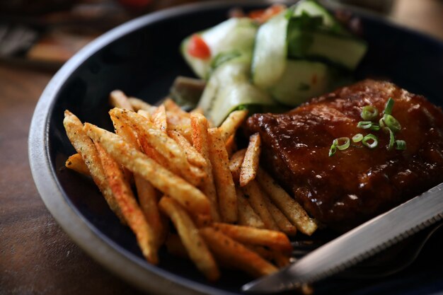 Filete de costillas de cerdo a la parrilla con verduras frescas en un viejo rústico de madera en restaurante