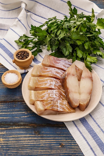 Filete crudo de carbonero. Rodajas frescas en un plato, especias, perejil. Un montón de verduras, servilleta vintage