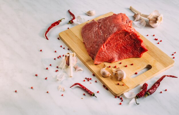 Filete crudo de cerdo fresco en el tablero de madera. Carne de res roja sobre una tabla para cortar.