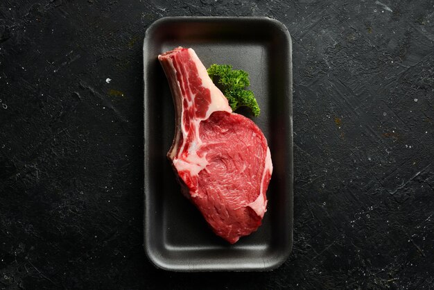 Filete crudo fresco de ternera en el hueso Sobre un fondo de piedra negra Alimentos orgánicos