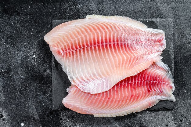 Filete crudo de tilapia en una tabla de cortar