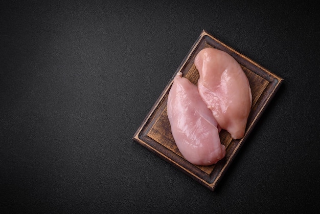 Filete de frango fresco em uma mesa de concreto escuro com especiarias e ervas