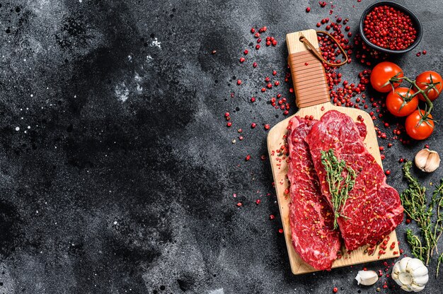 Filete de Denver sobre una tabla de cortar carne de vacuno cruda de mármol