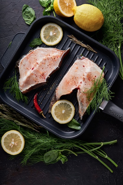 Filete fresco de pescado de mar en una cacerola de la parrilla en fondo oscuro.