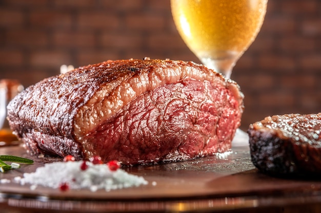 Filete de lomo de tapa en rodajas a la parrilla sobre tabla de cortar de madera con un vaso de cerveza (picanha brasileña).