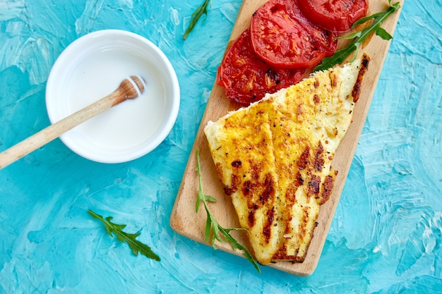 Filete de lucio a la plancha con tomate sobre tabla de madera