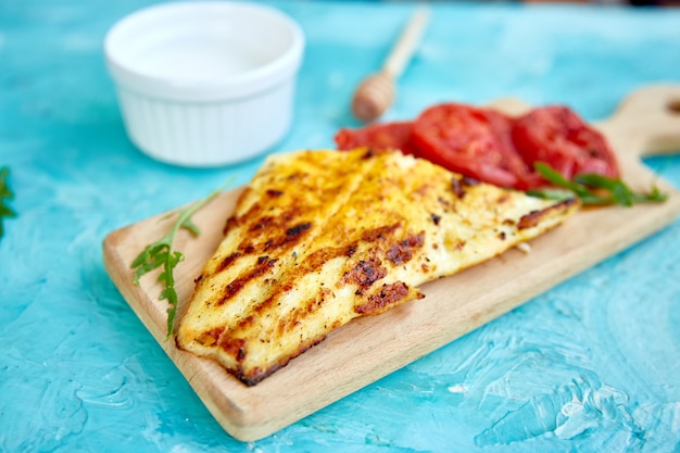 Filete de lucio a la plancha con tomate sobre tabla de madera