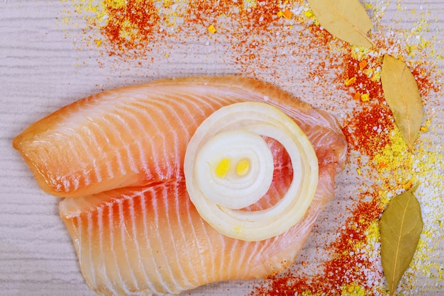 Filete marinado de tilapia con laurel y cebolla, en tabla para cortar