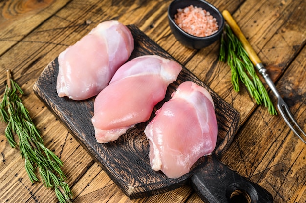 Filete de muslo de pollo crudo deshuesado. Mesa de madera. Vista superior.