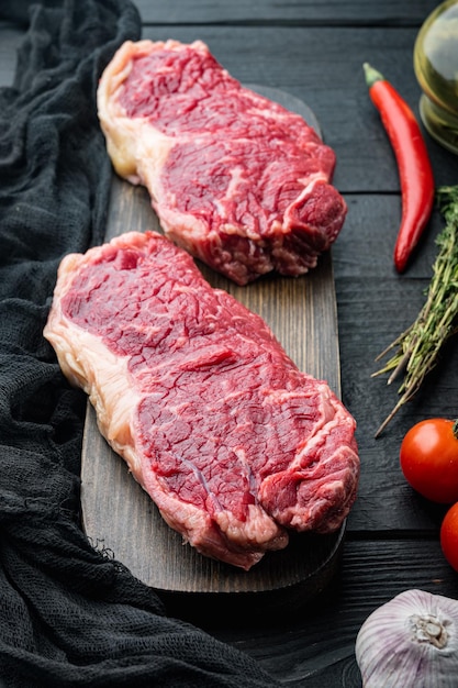 Filete de Nueva York, carne de vacuno cruda, sobre fondo de madera negra