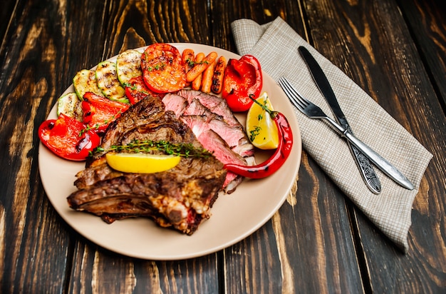 Filete a la parrilla y verduras a la parrilla en un plato sobre madera