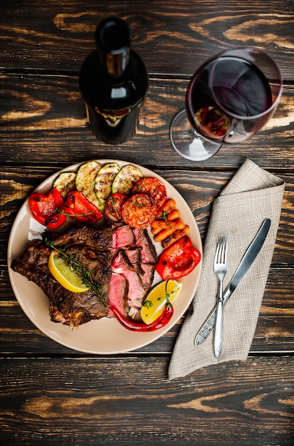 Filete a la parrilla y verduras a la parrilla en un plato sobre madera