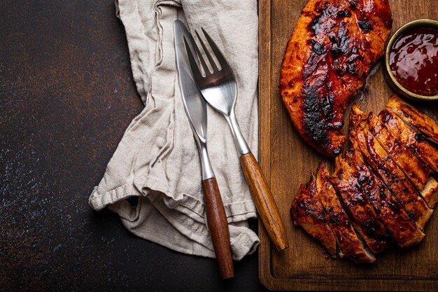 Filete de pavo o pollo a la parrilla con salsa roja servido y rebanado en una tabla de cortar de madera