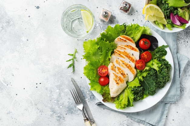 Filete de pechuga de pollo y ensalada de verduras con tomates y hojas verdes. El concepto de comida sana y dieta cetogénica. Vista superior.