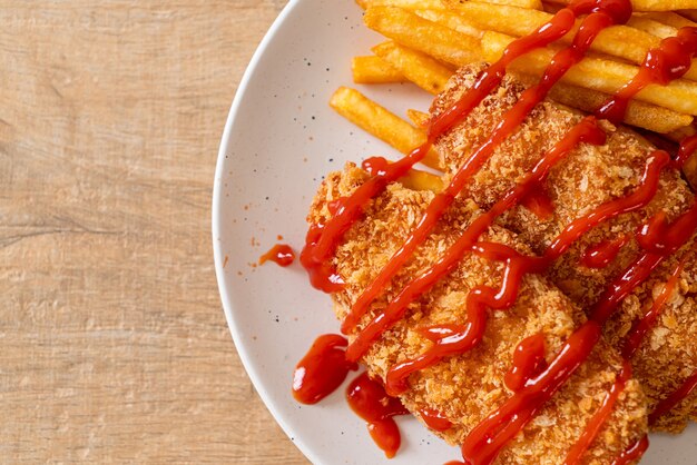 Foto filete de pechuga de pollo frito con papas fritas y salsa de tomate