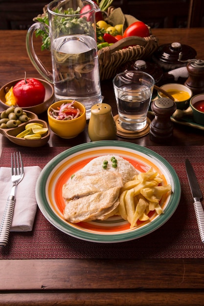 Foto filete de pechuga de pollo papas fritas comida tradicional peruana mise en place mesa de madera