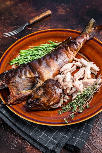 Filete de perca de pescado ahumado caliente en plato rústico con tomillo. Fondo oscuro. Vista superior.