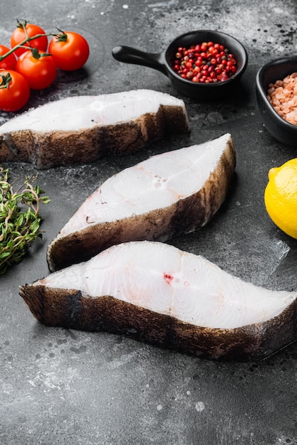 Filete de pescado de agua salada de halibut crudo, con ingredientes y hierbas de romero, sobre fondo de mesa de piedra oscura negra