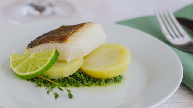 Filete de pescado al horno con guarnición y salsa en la mesa del restaurante.