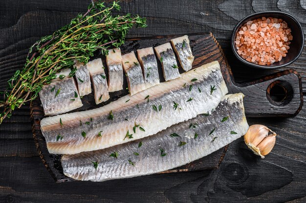 Filete de pescado arenque salado en rodajas sobre una tabla de madera