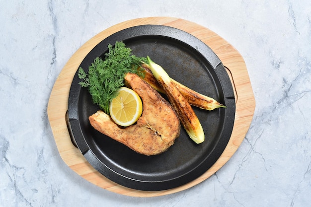 Filete de pescado con calabacín al horno y hierbas sobre una tabla de madera. Platos de pescado. Vista superior