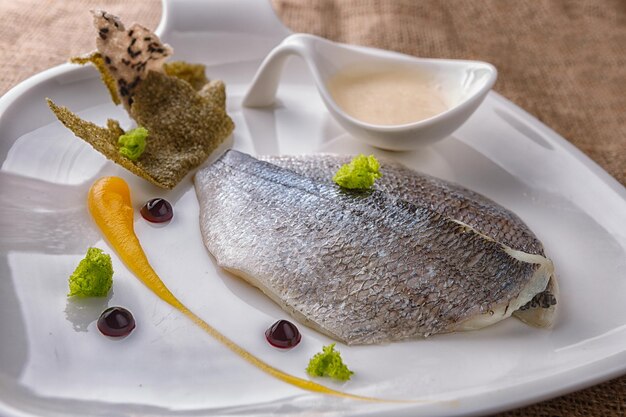 Filete de pescado dorado al horno con salsa en un plato