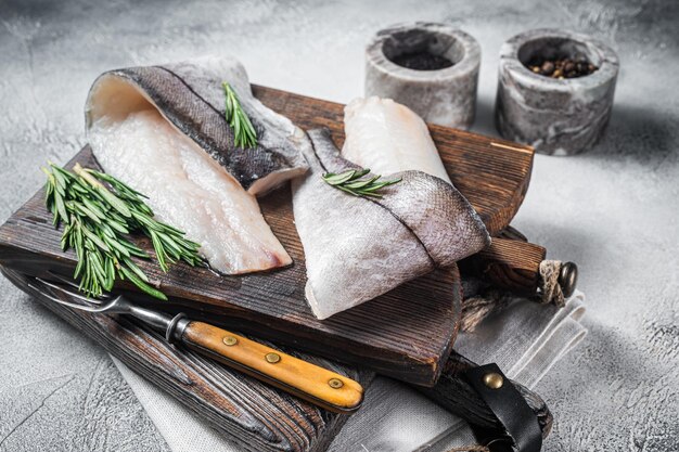 Filete de pescado de eglefino carne de marisco crudo sobre tabla de madera con hierbas Fondo blanco Vista superior