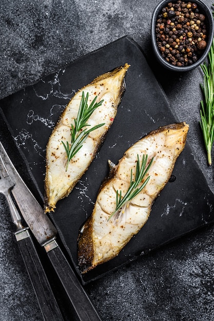 Filete de pescado de fletán con romero. Fondo negro. Vista superior.