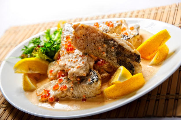 Filete de pescado frito con papas fritas en un plato blanco.