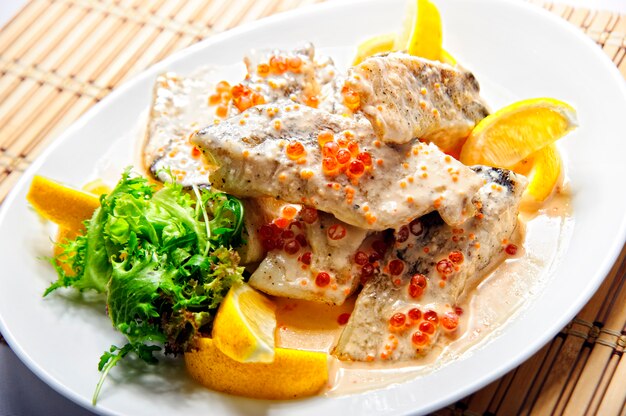 Filete de pescado frito con papas fritas en un plato blanco.