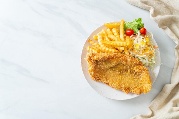 Filete de pescado frito y patatas fritas con mini ensalada
