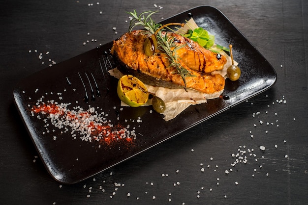 Filete de pescado grande a la parrilla en el fondo de madera negra