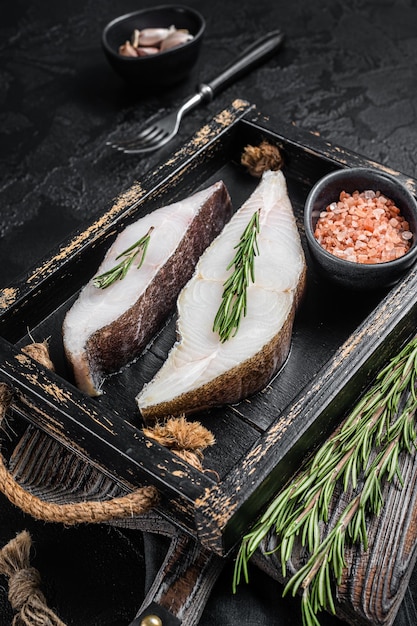 Filete de pescado de halibut crudo en bandeja de madera con hierbas Fondo negro Vista superior