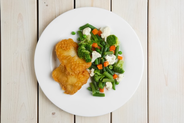 Foto filete de pescado en masa con verduras hervidas