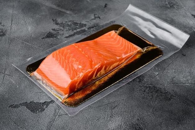 Filete de pescado rojo en conjunto de envasado al vacío, sobre fondo de tabla de piedra gris, con espacio para copiar texto