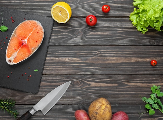 Filete de pescado rojo fresco en una mesa de madera oscura con verduras