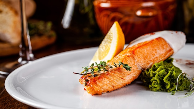 Filete de pescado rojo con limón sobre una placa blanca.