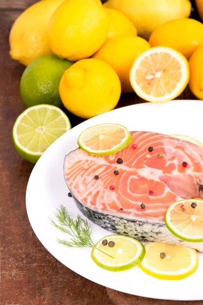 Foto filete de pescado rojo y limones en rodajas sobre mesa de madera